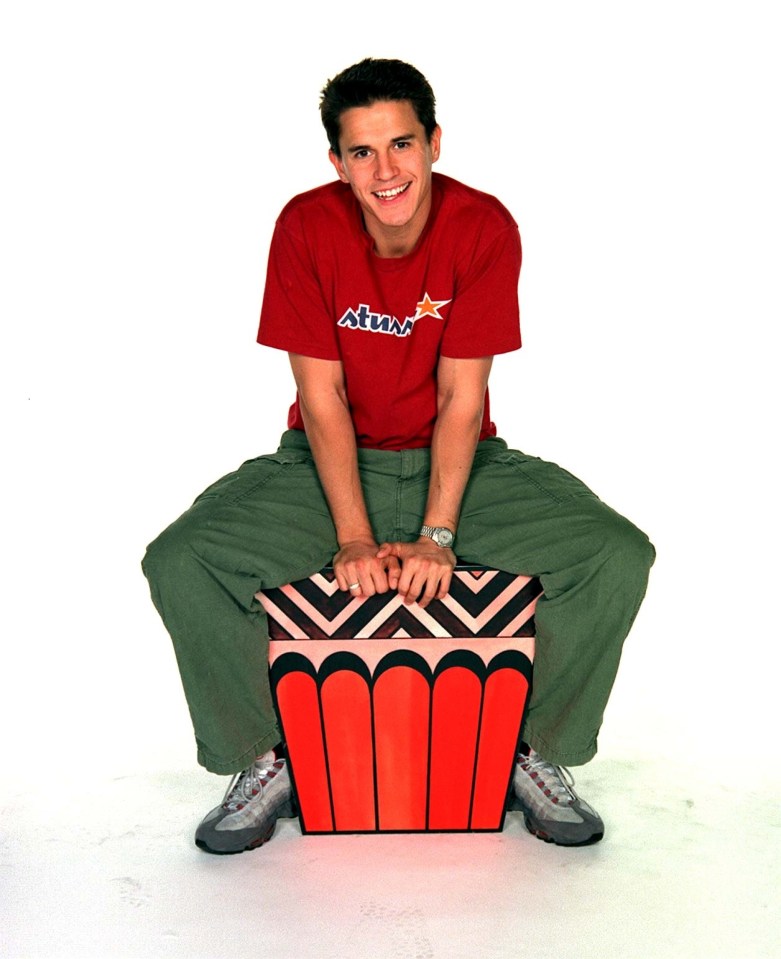 Jeremy Edwards, TV presenter, sitting on a large cupcake prop.