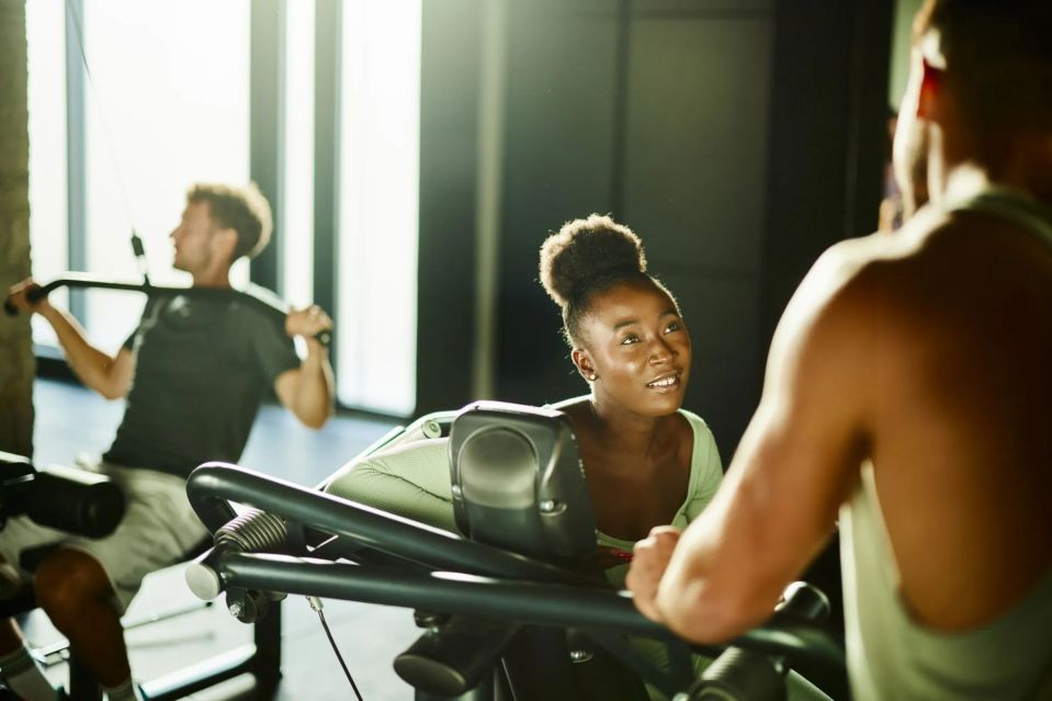 Woman talking to a man in a gym.