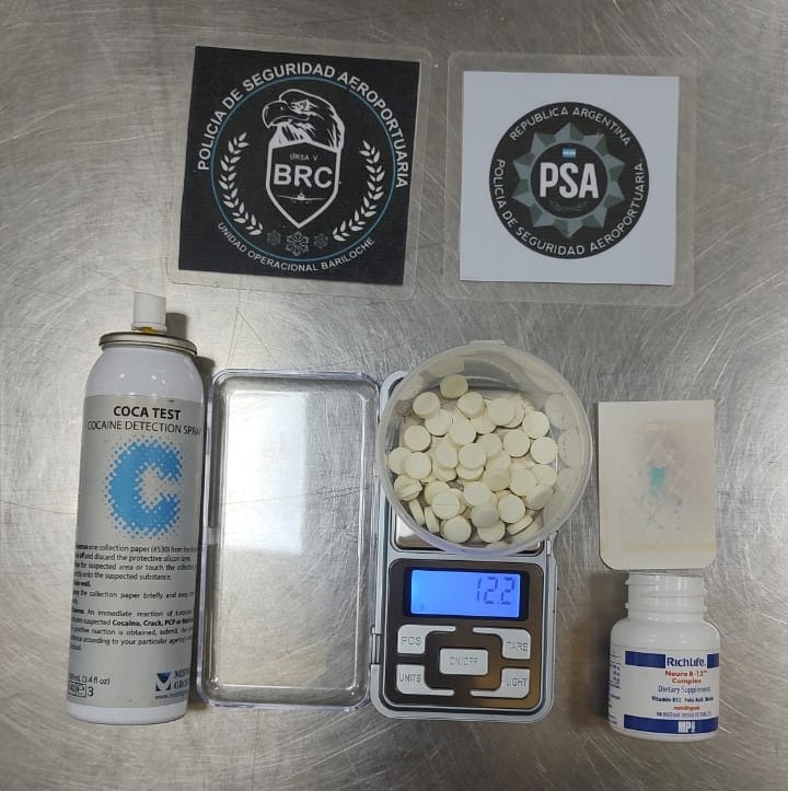 Seized pills, cocaine test spray, and police insignia.