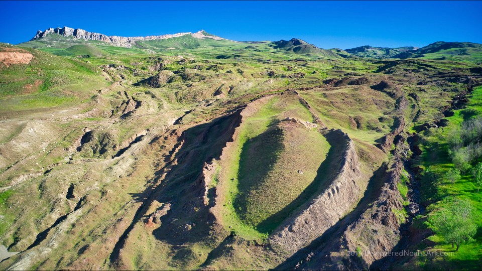 Aerial view of a mountainous landscape with eroded hillsides and a valley.