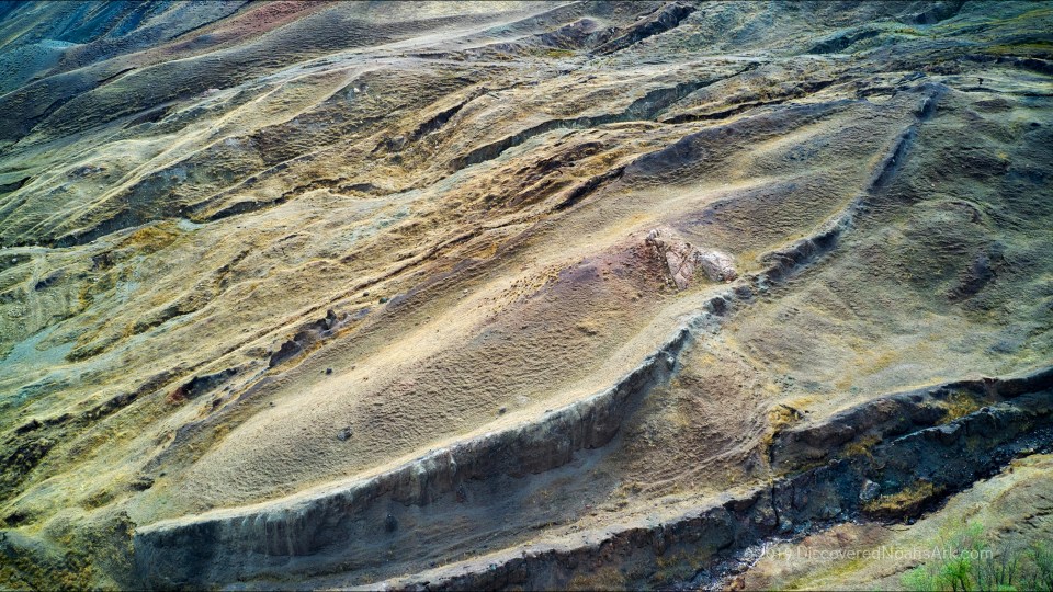 Aerial view of layered, multicolored earth formations.