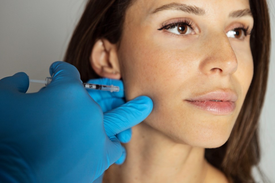 Close-up of a woman receiving a botox injection in her jaw.