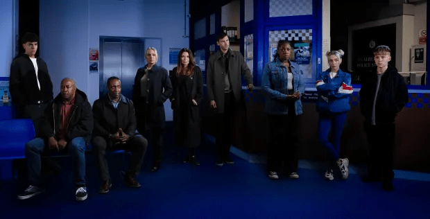 Group of people standing in a police station waiting area.