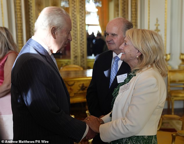 King Charles speaks with Alistair and Heather James, the parents of the late broadcaster Deborah James, during a reception in Buckingham Palace