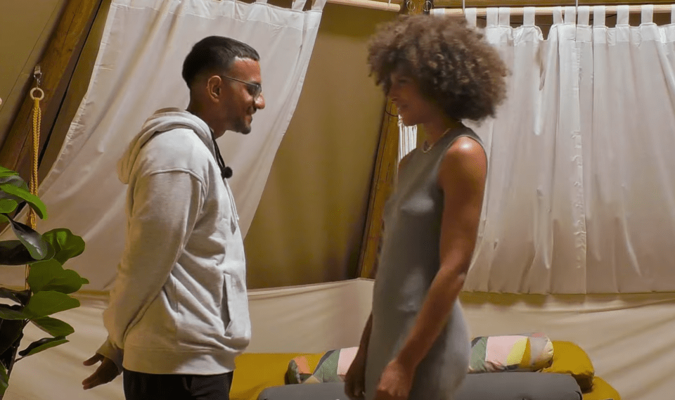 Screenshot of a man and woman facing each other in a tent.