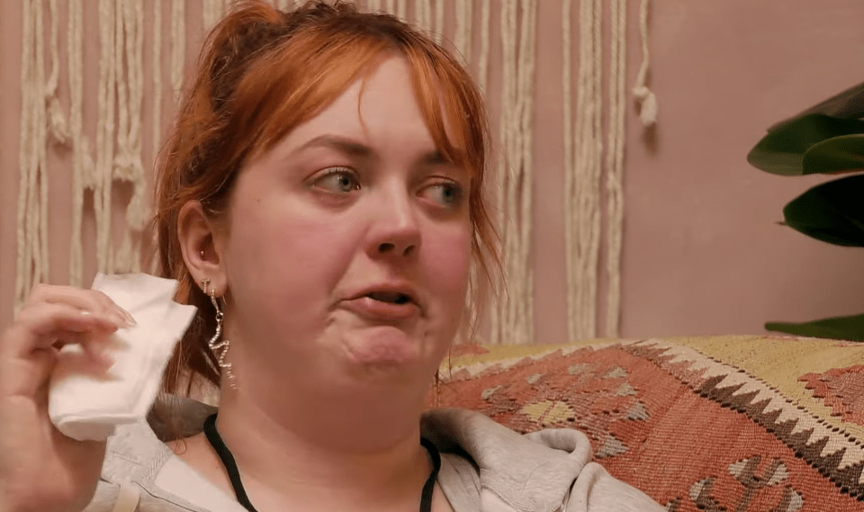 Screenshot of a young woman wiping her face with a tissue.