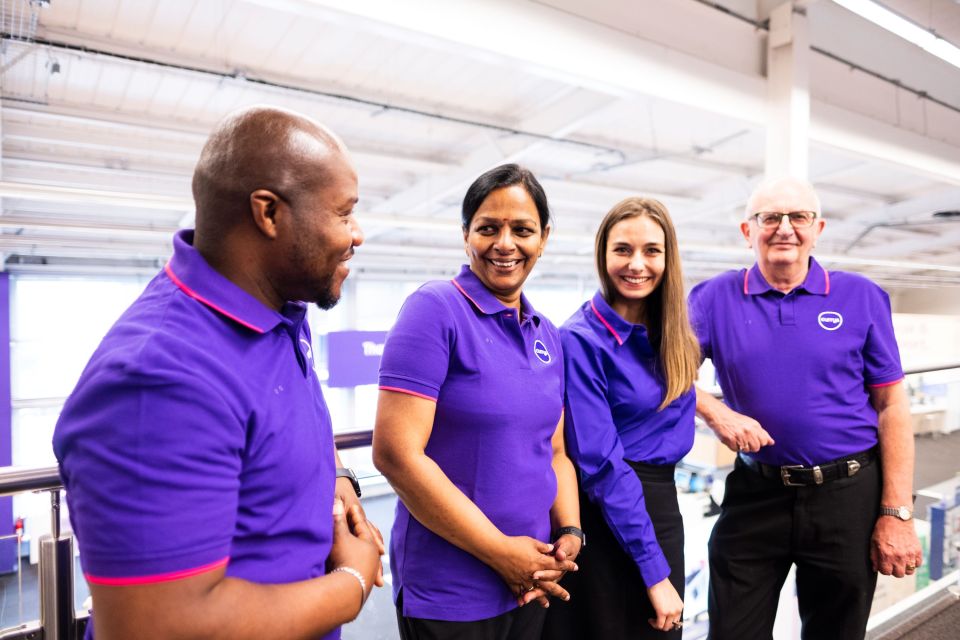Four Currys employees in purple polo shirts.
