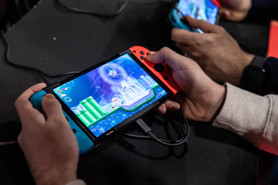 Two people playing a video game on Nintendo Switch consoles at Milan Games Week.