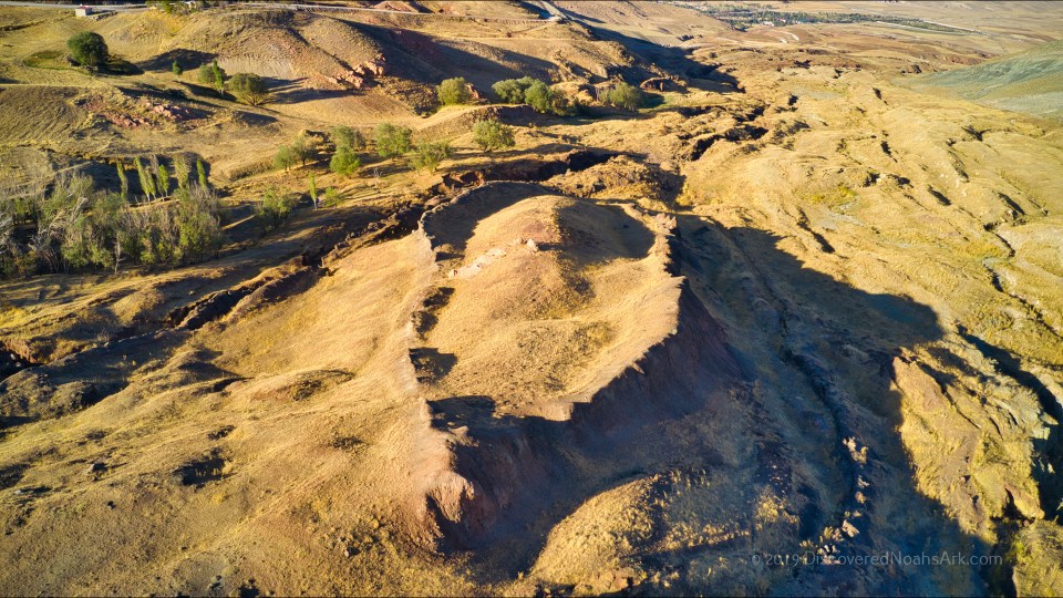 Aerial view of ancient ruins in a dry, hilly landscape.