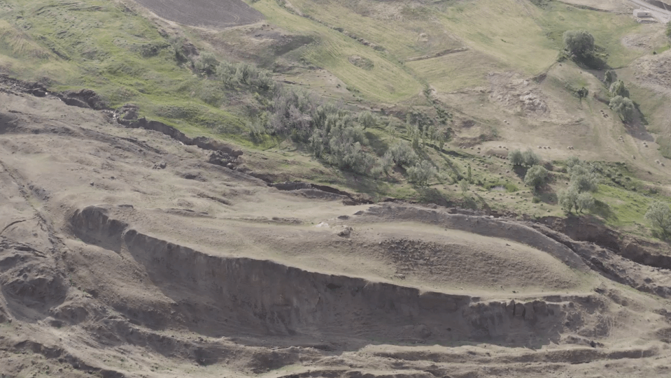 Aerial view of a dry, hilly landscape with sparse vegetation.