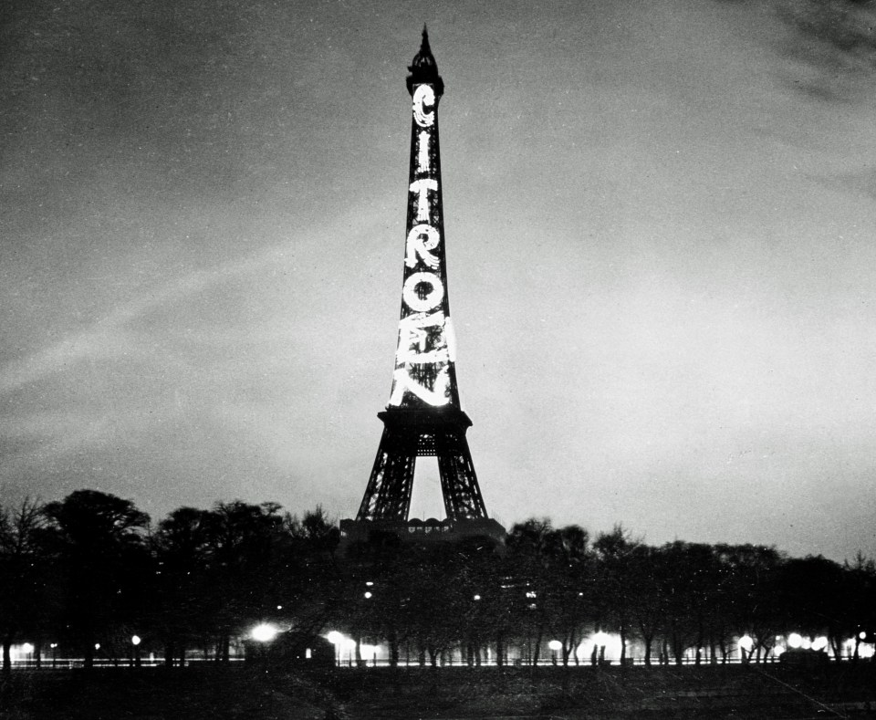 Black and white photo of the Eiffel Tower with "CITROËN" illuminated on its side.