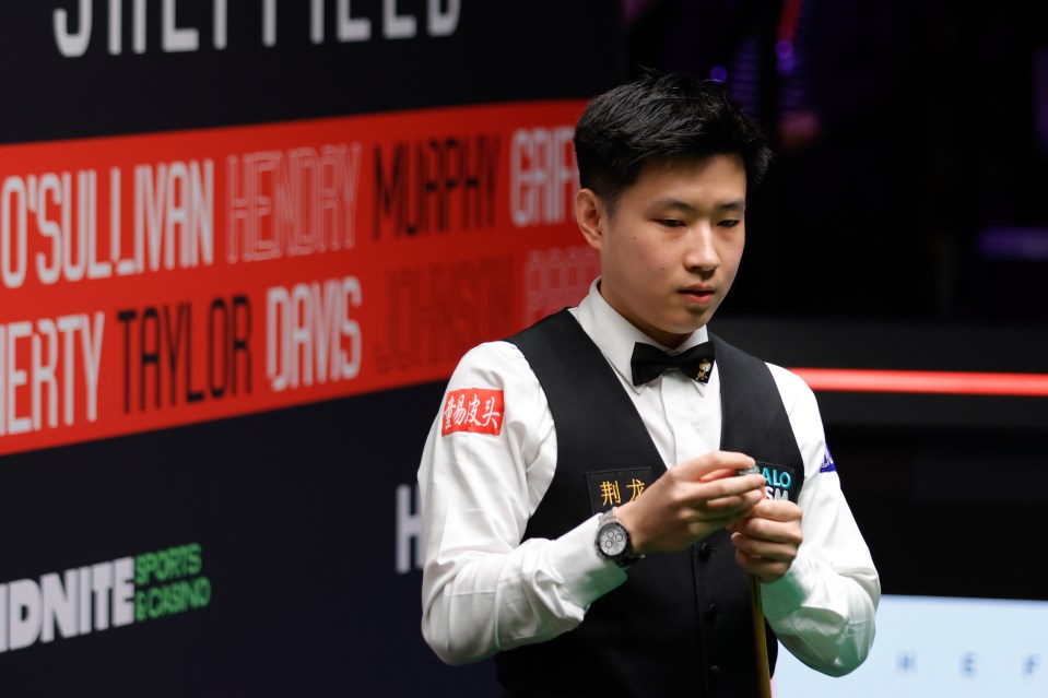 Zhao Xintong chalking his cue at a snooker match.