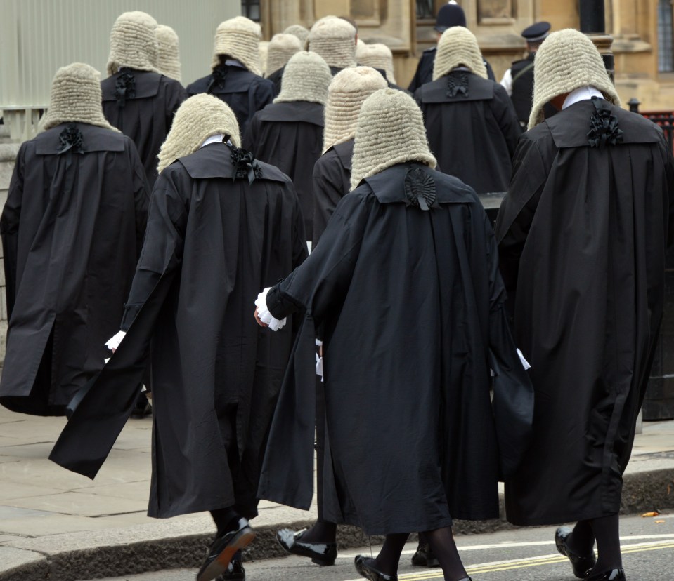 British judges in traditional robes and wigs walking in procession.