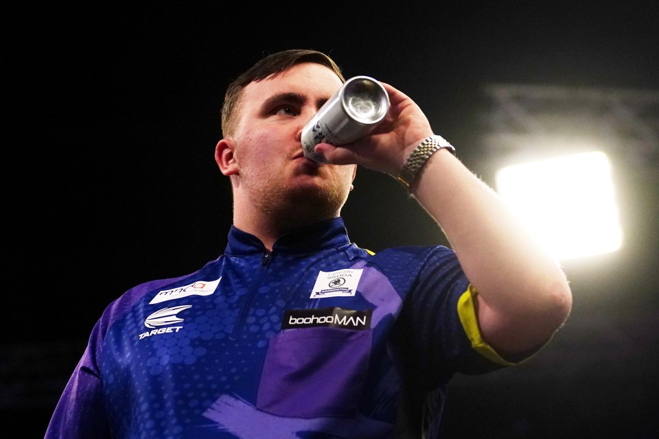 Luke Littler drinking water during a darts match.