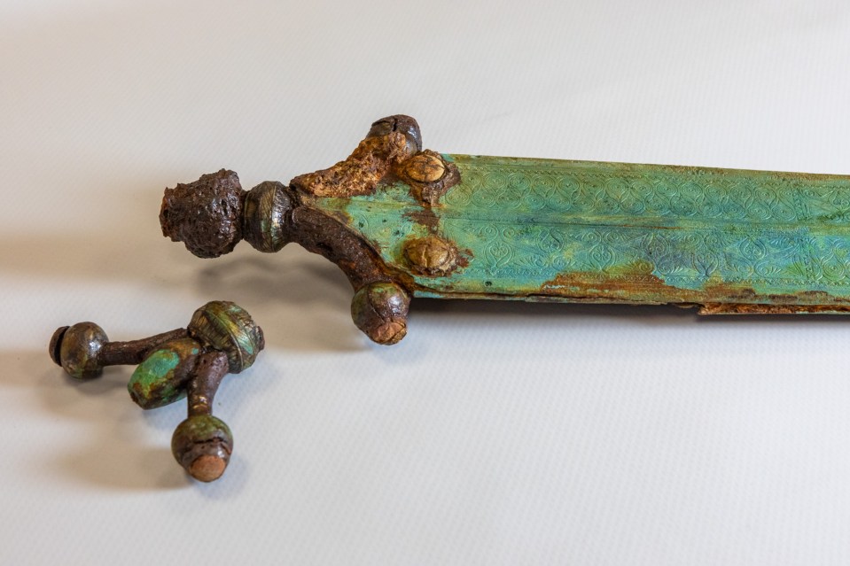 Rusty, ornamented metal sword and its broken hilt.