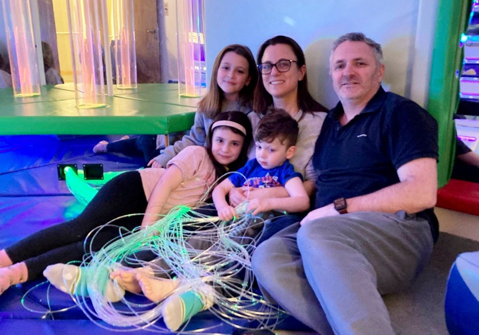Family with three children sitting on a sensory mat.