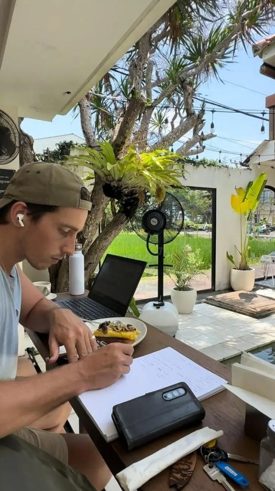 Person working on laptop at outdoor cafe.