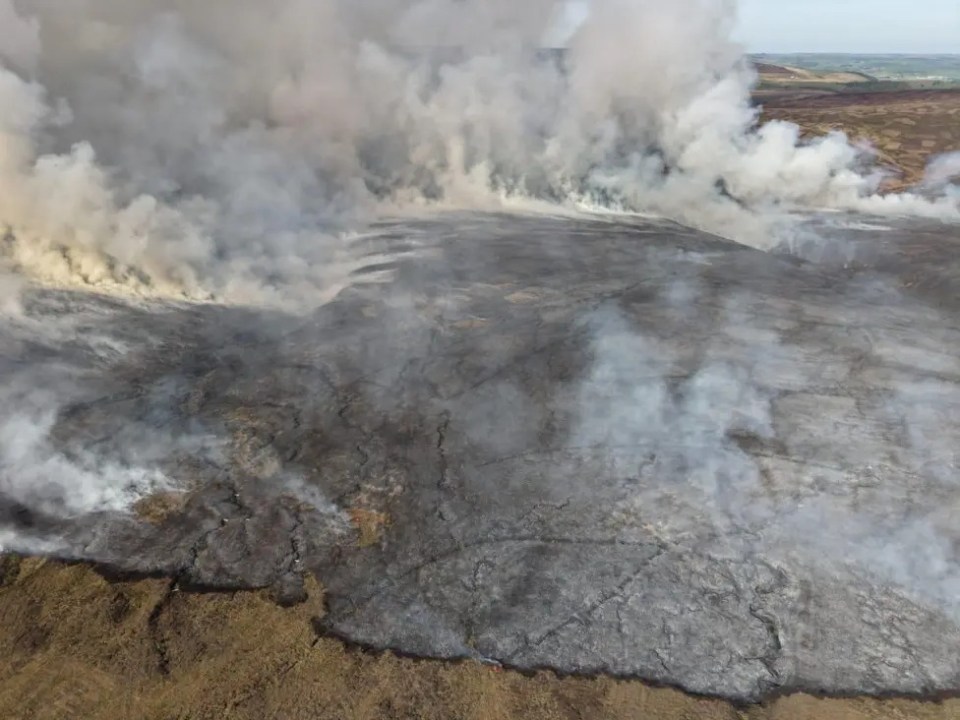 Aerial view of a large moorland fire with smoke billowing.