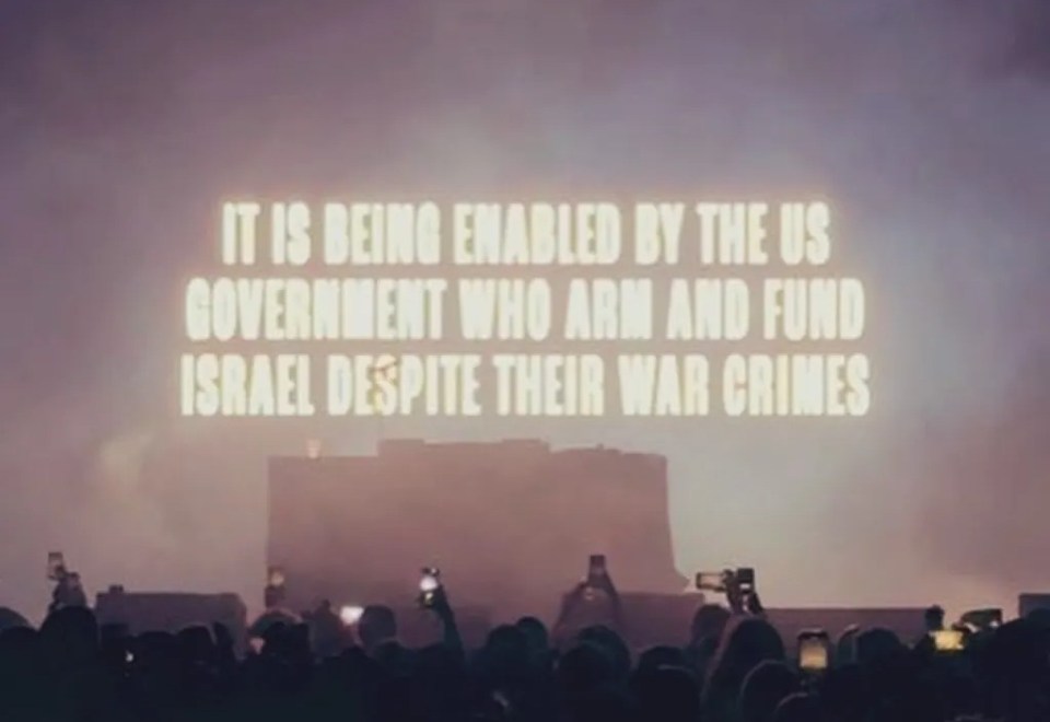Crowd at a concert with a statement about US government support for Israel.