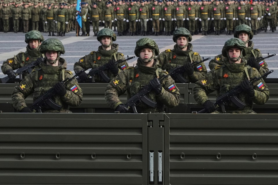 Russian soldiers with rifles in a truck during a military parade rehearsal.