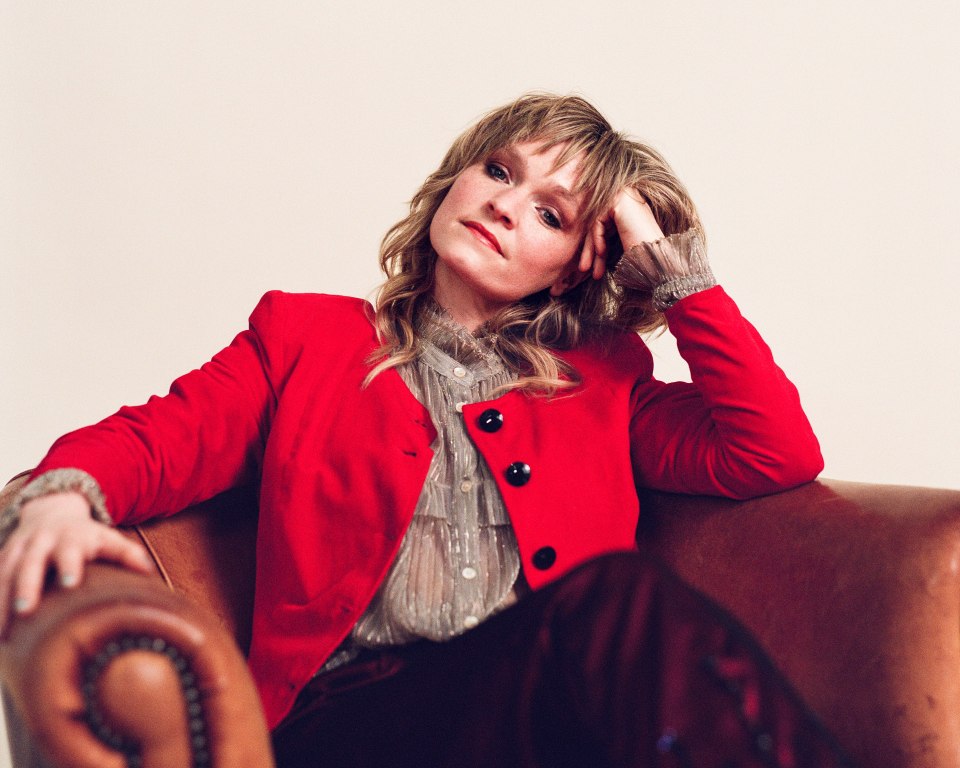Portrait of Billy Nomates in a red jacket.