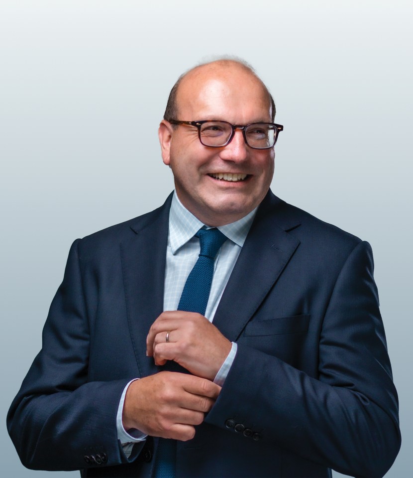Portrait of a smiling man in a suit adjusting his cufflinks.