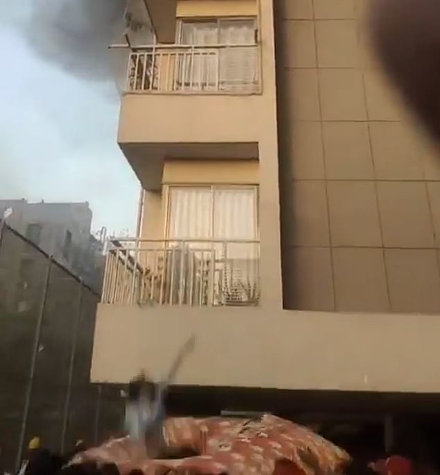 Miraculously, she is safely caught by a crowd of people who had gathered below the building, in Ahmedabad, India, after noticing it was on fire