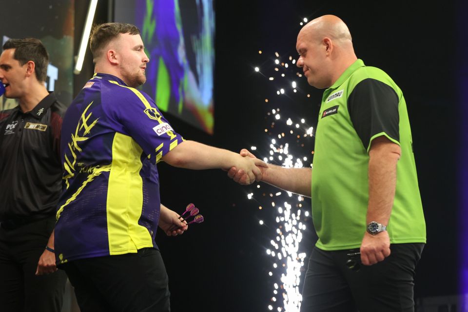 Luke Littler and Michael van Gerwen shaking hands after a darts match.