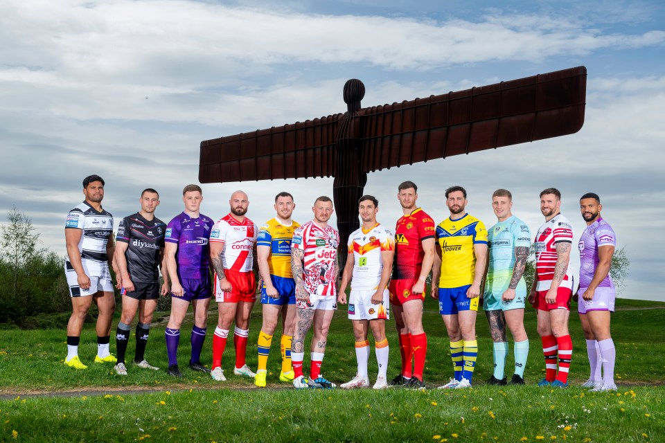 Rugby players in various team jerseys posing in front of the Angel of the North.