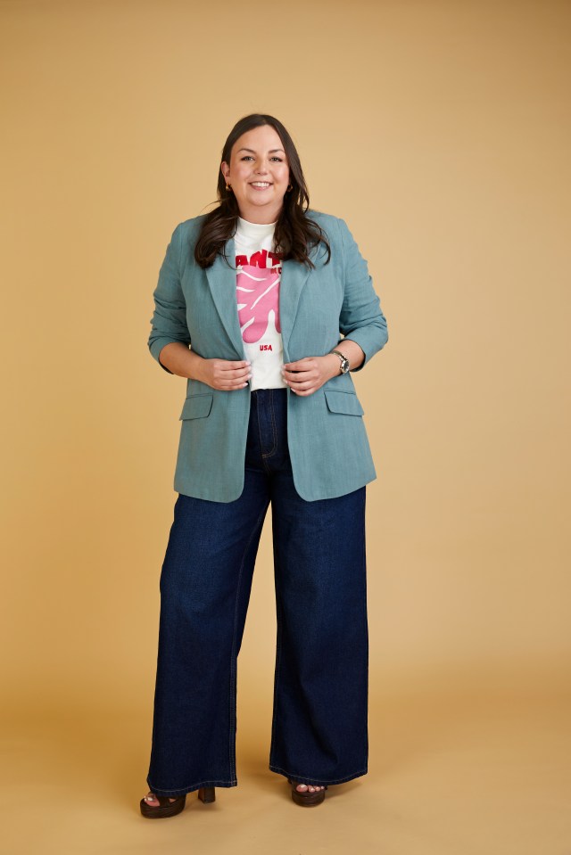 Woman in teal blazer and wide-leg jeans.