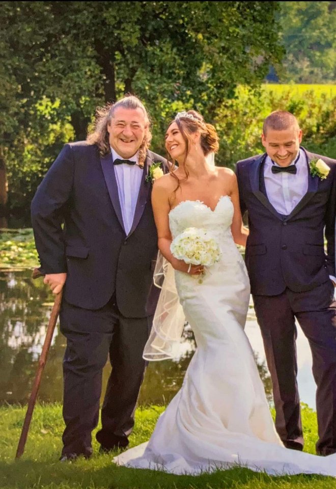 A bride and groom with the bride's father at their wedding.