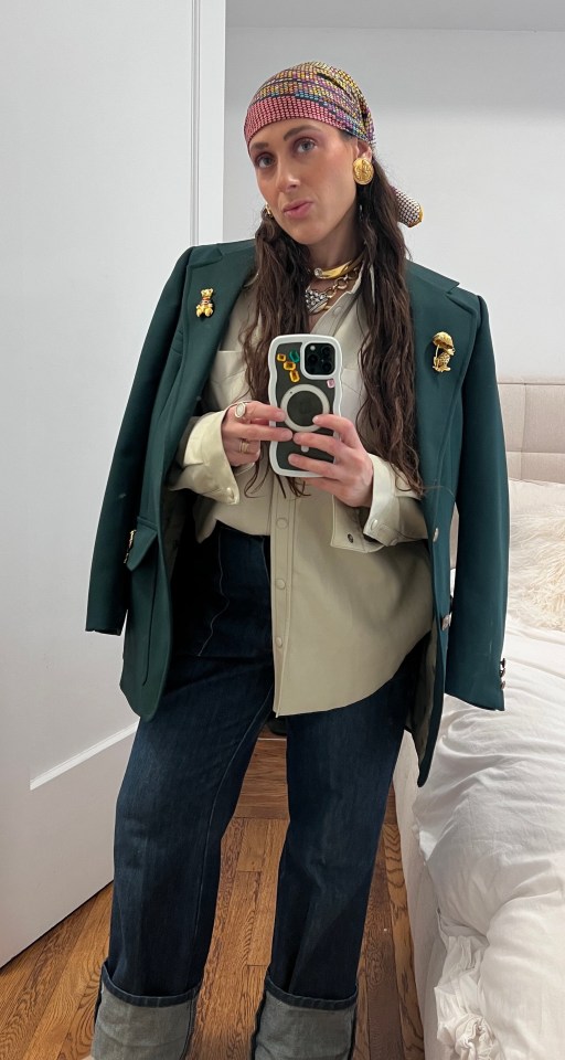 Woman in a green blazer and jeans taking a selfie.