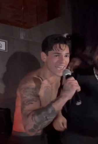 Man with tattoos singing into a microphone.