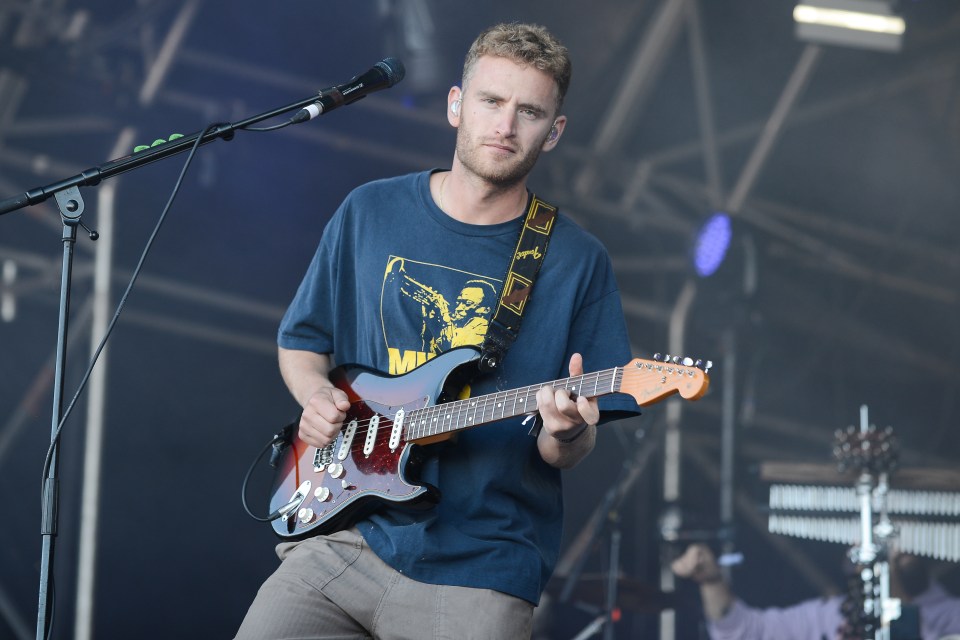 Tom Misch performing at a music festival, playing an electric guitar.