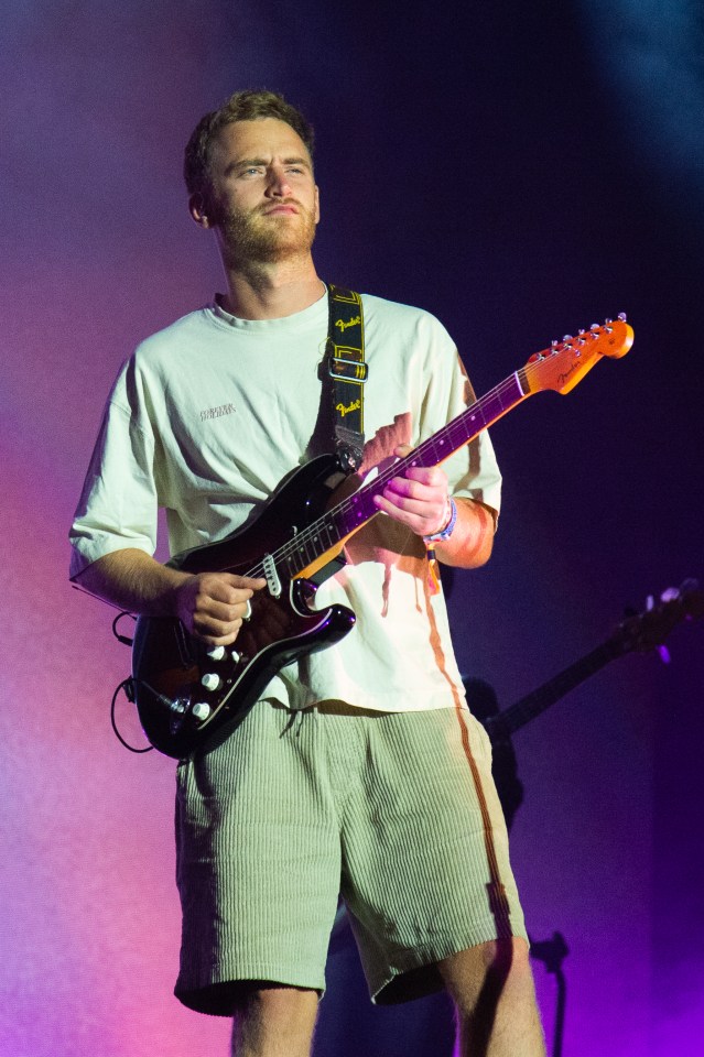 Tom Misch performing at a music festival, playing an electric guitar.