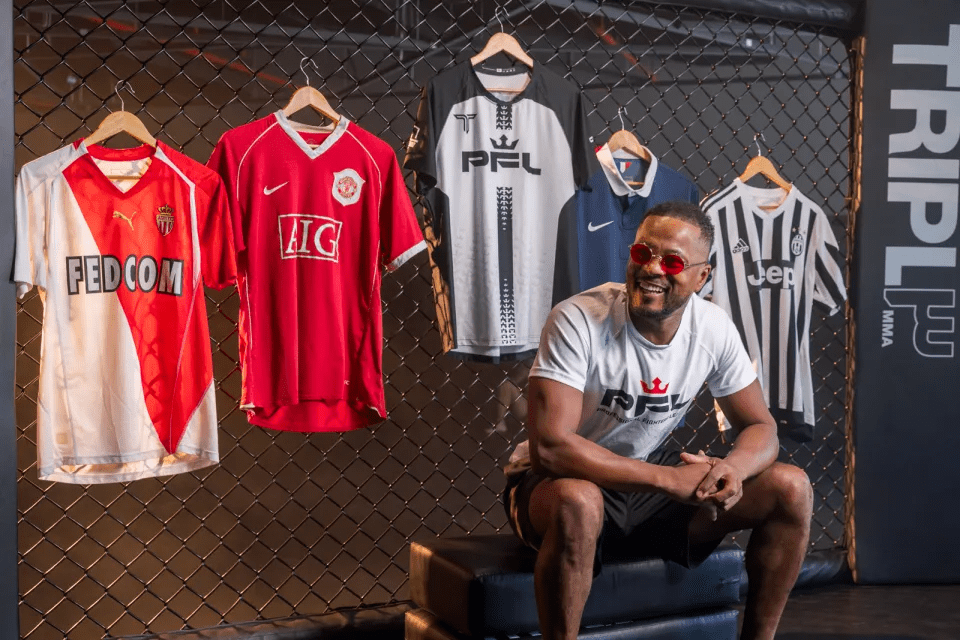 Man in sunglasses sits smiling in front of several jerseys.