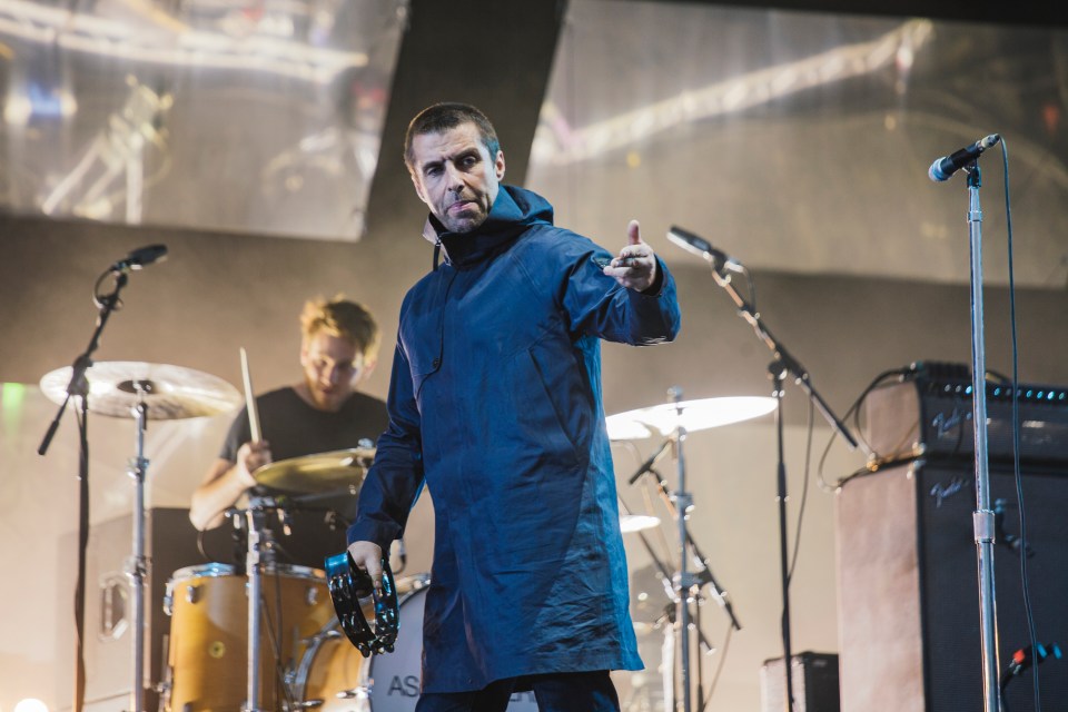 Liam Gallagher performing on stage at a music festival.