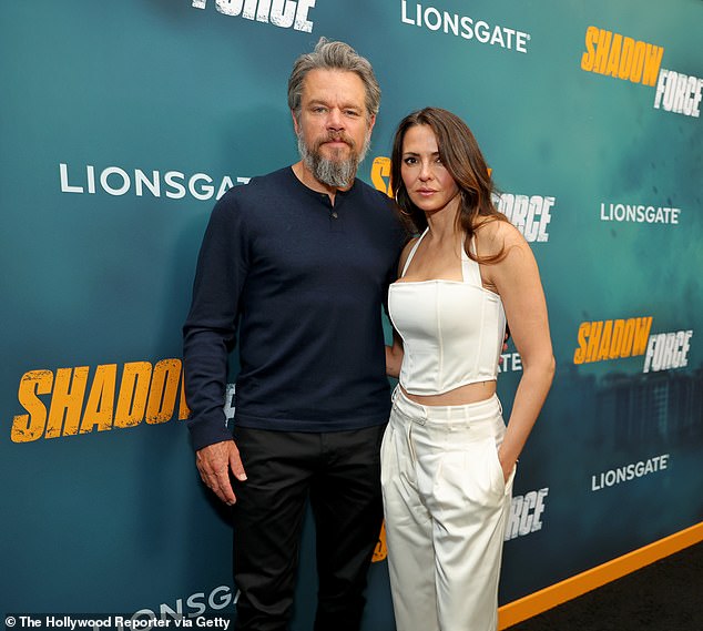 At his side, his wife flaunted her fit physique in a cream-colored, satin corset top paired with matching, high-waisted trousers and brown, leather mules