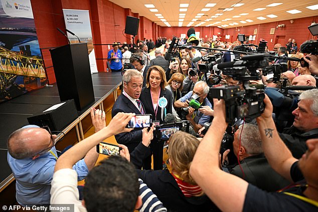 Nigel Farage (L), leader of the Reform UK party and Sarah Pochin (R), the party's candidate, speak with the press as they celebrate her victory in the Runcorn & Helsby by-election at the DCBL Stadium