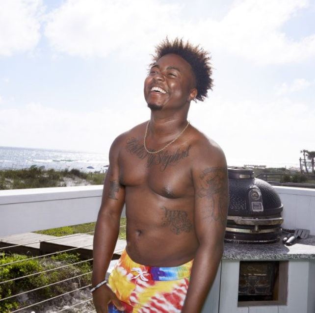 Kirk Medas, shirtless, smiling, on a beach.