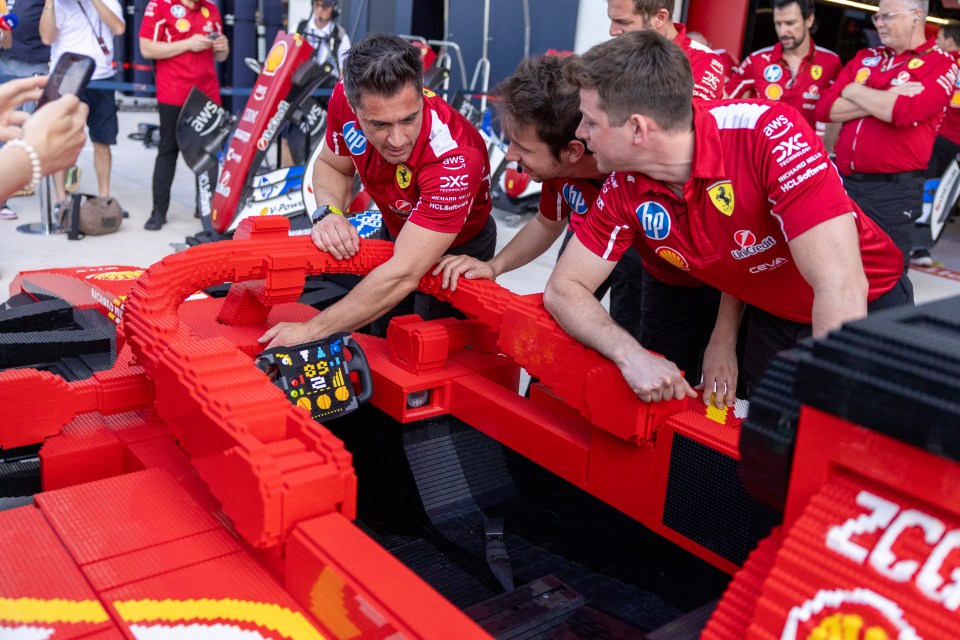 Ferrari mechanics examining a large Lego model of a Formula 1 car.