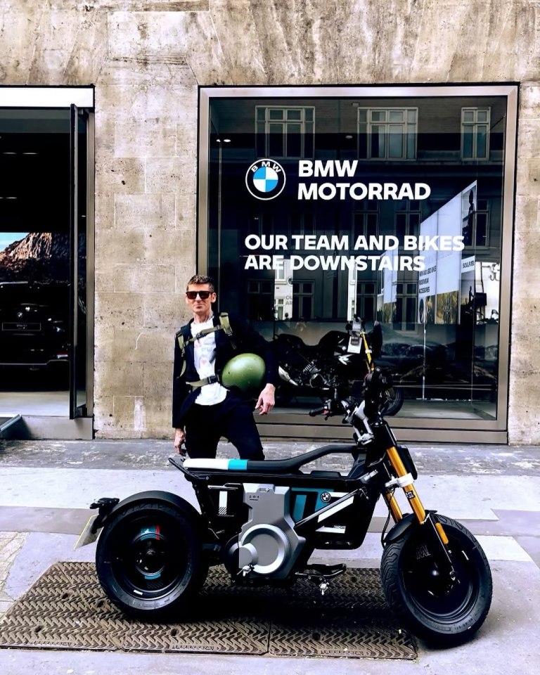 Man standing next to an electric BMW motorcycle outside a BMW Motorrad store.