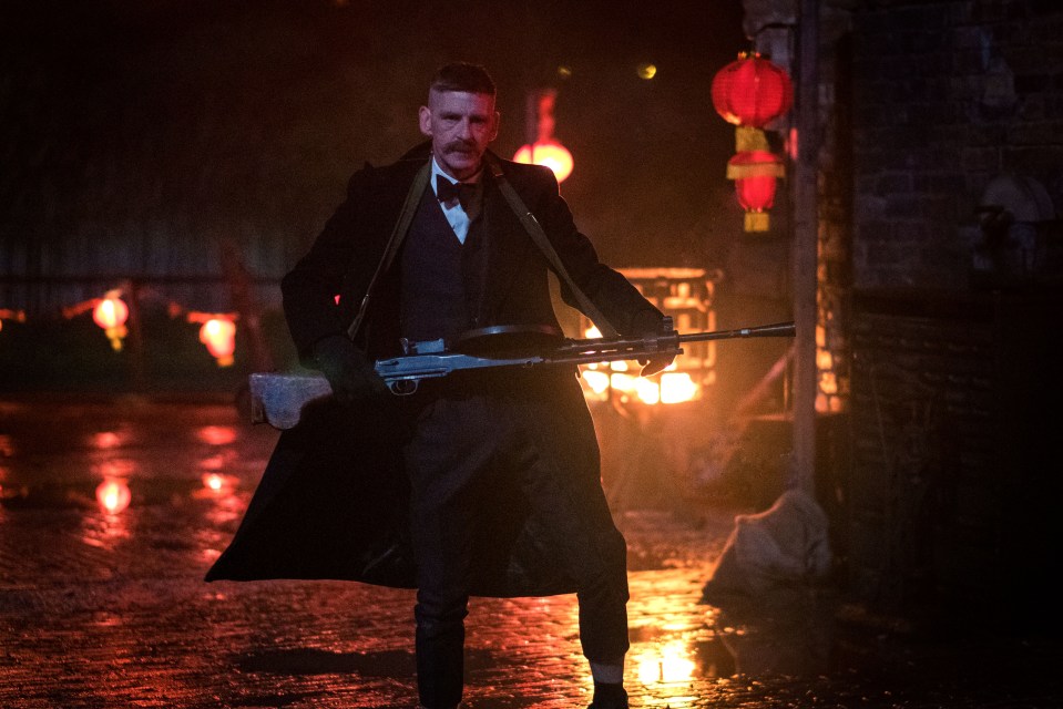 Arthur Shelby from Peaky Blinders carrying a machine gun.