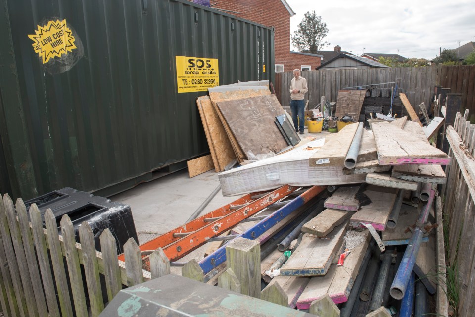 Pile of building materials and ladders outside a home.