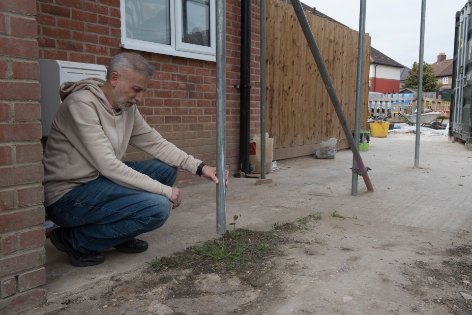 Man inspecting a scaffolding tube at a home renovation site.