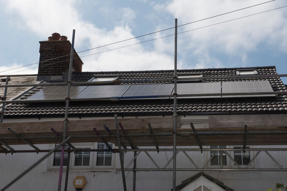 Solar panels installed on a house roof with scaffolding.