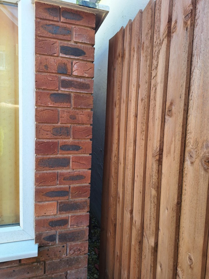 Brick wall and wooden fence separating two properties.