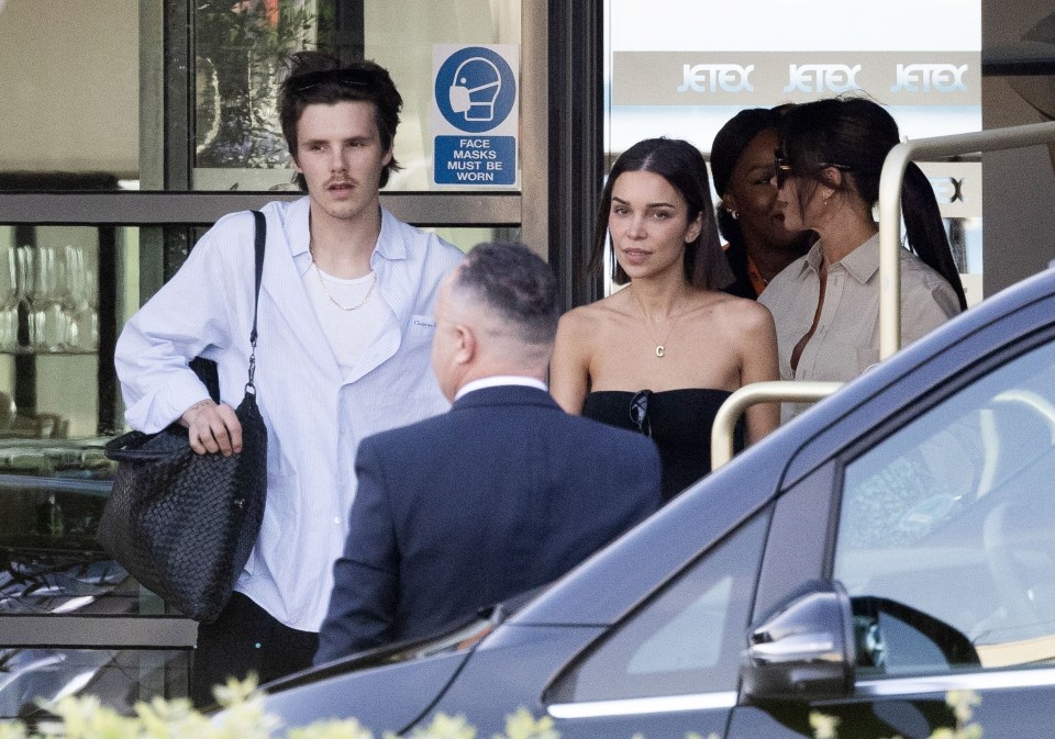 Romeo Beckham and his girlfriend arriving at an airport.