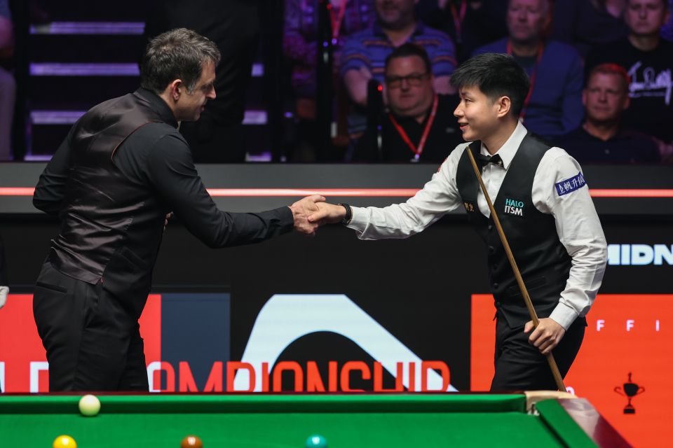 Zhao Xintong and Ronnie O'Sullivan shaking hands before a snooker match.