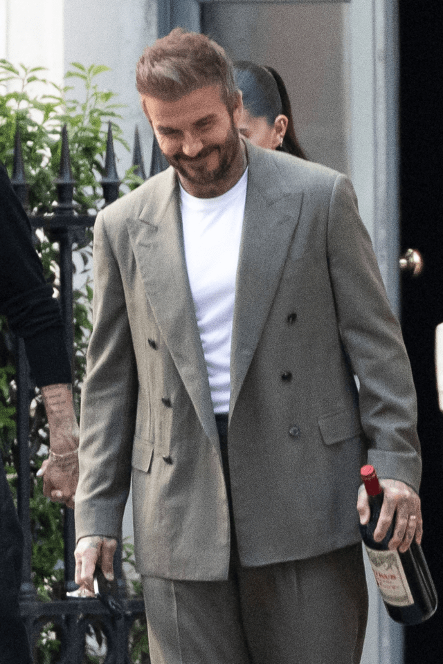 Man in suit carrying a bottle of wine.